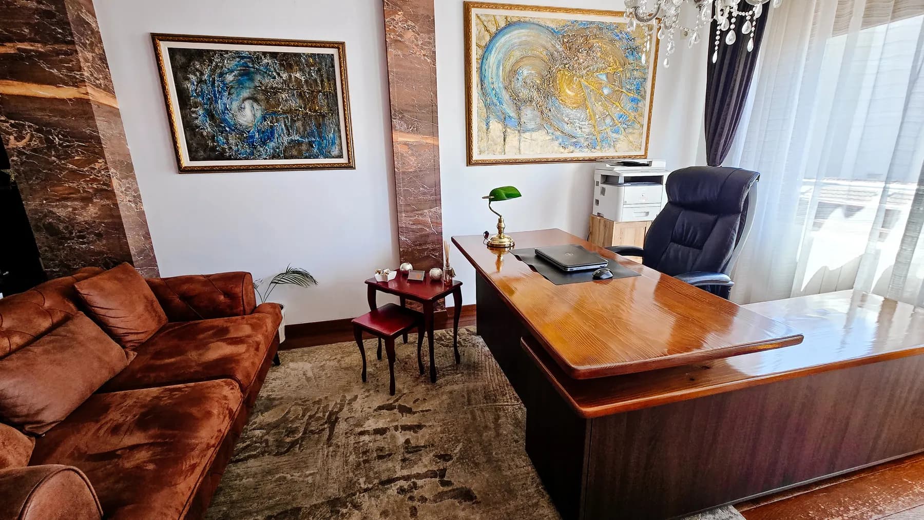 Radni prostor advokatske kancelarije Krnić: radni sto, garnitura za razgovor sa strankama i umetničke slike na zidu